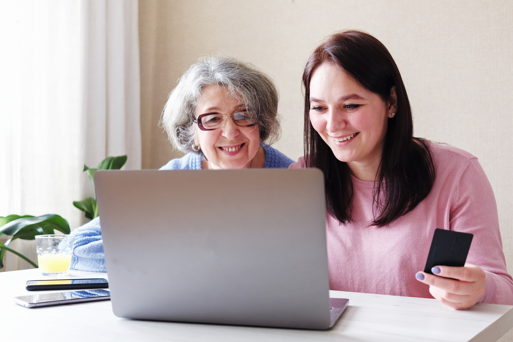 A daughter with an elderly mother makes online purchases - Helping the elderly to use a laptop computer and modern technologies - Safe shopping for self-isolation during the coronavirus epidemic