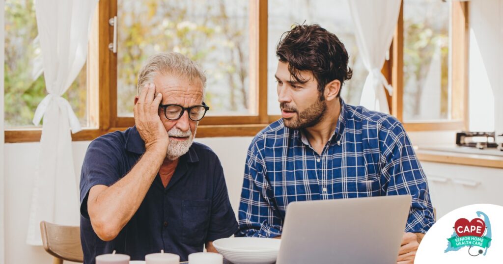 A man looks at a computer with his father who is confused, representing one of the early signs of dementia.